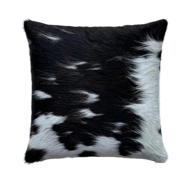 A square cowhide cushion with a black and white spotted pattern.