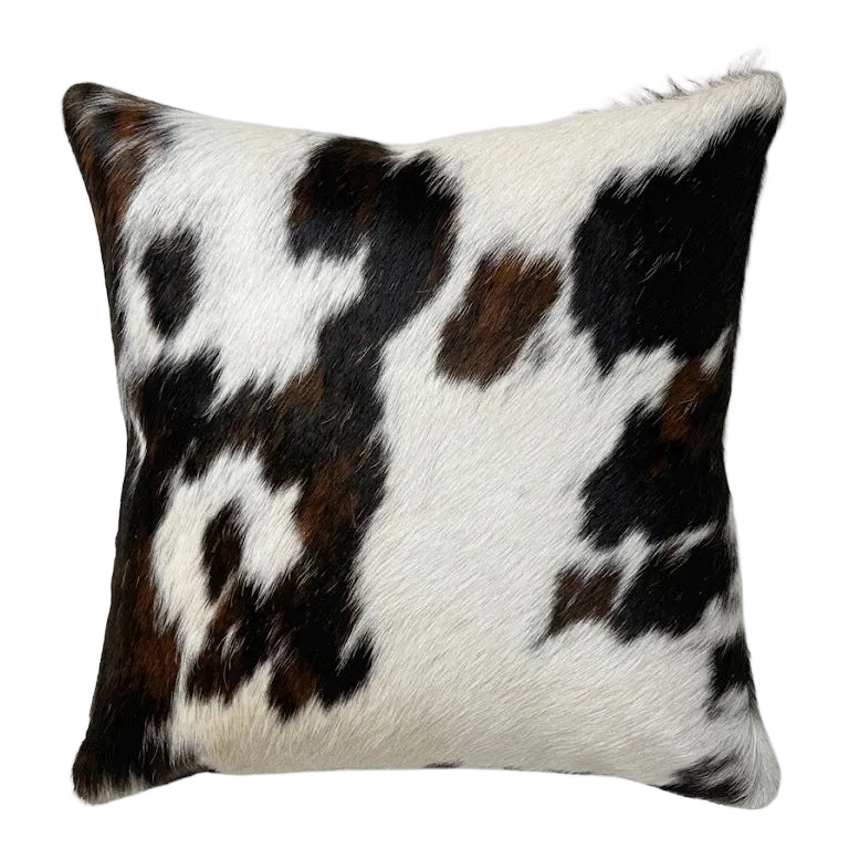 A square cushion with a black, brown, and white cowhide pattern.
