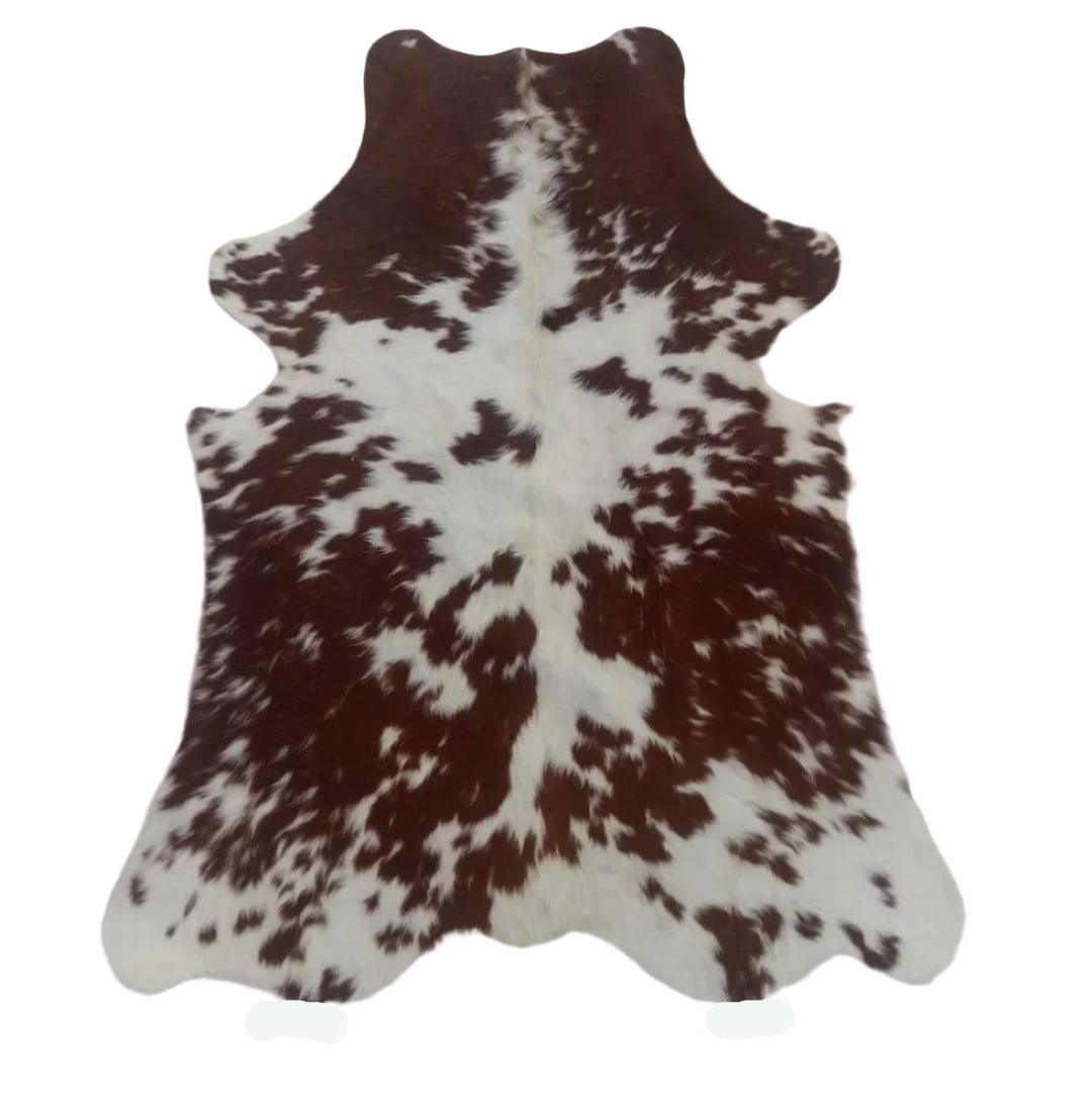 A brown and white cowhide rug laid flat on a white  surface.