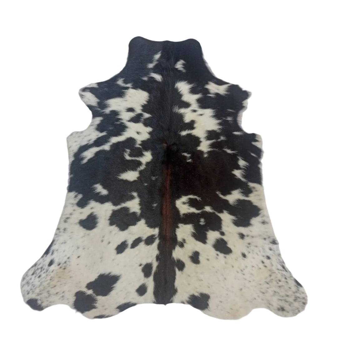 A black and white spotted cowhide rug laid flat on a white  surface.