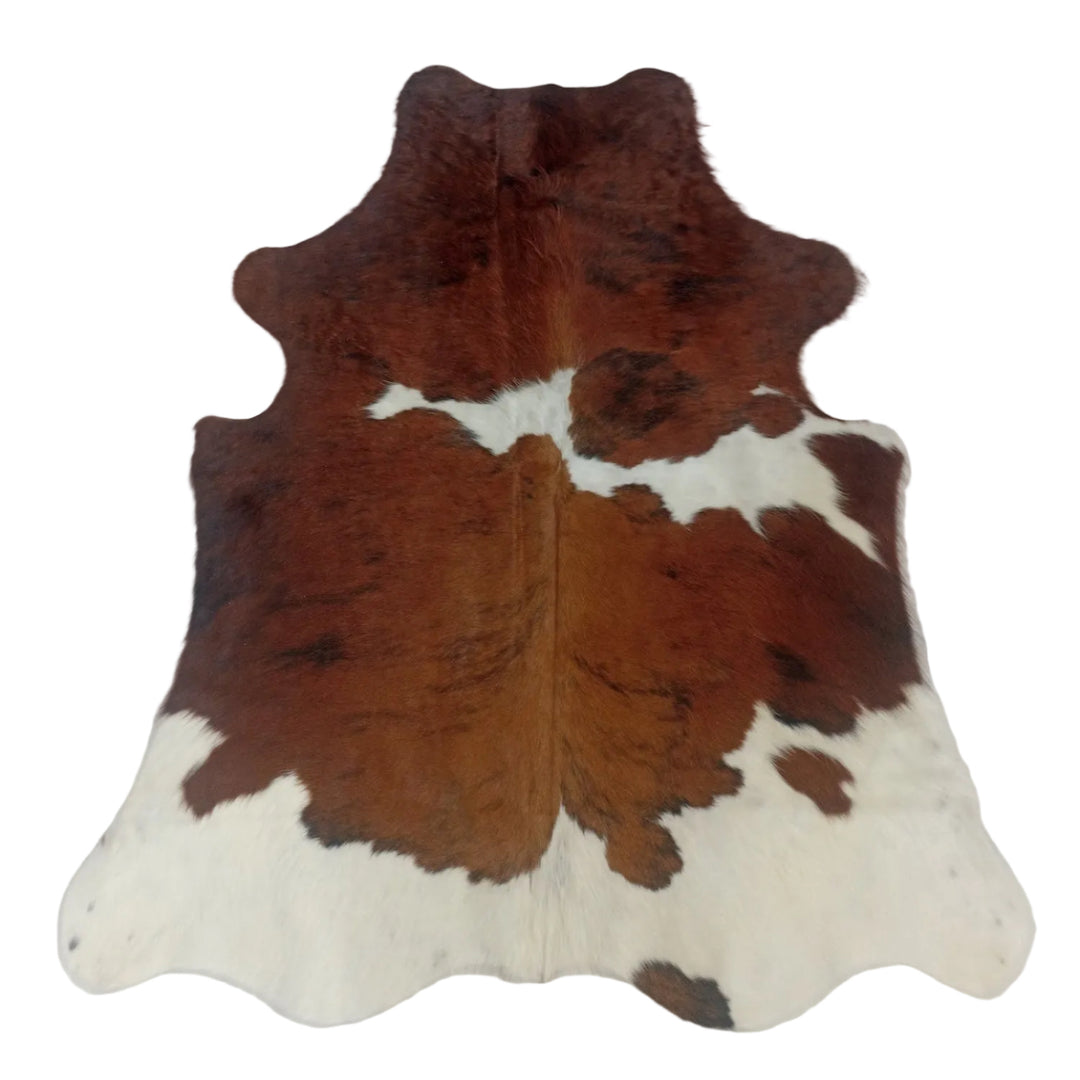 A natural cowhide rug with a brown and white mottled pattern, laid flat on a light-colored surface.