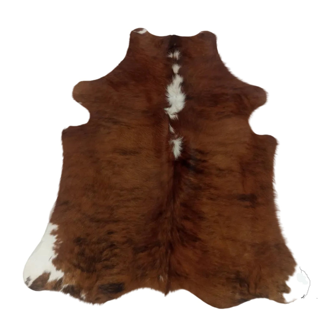 Brown and white cowhide rug laid flat on a light-colored surface.