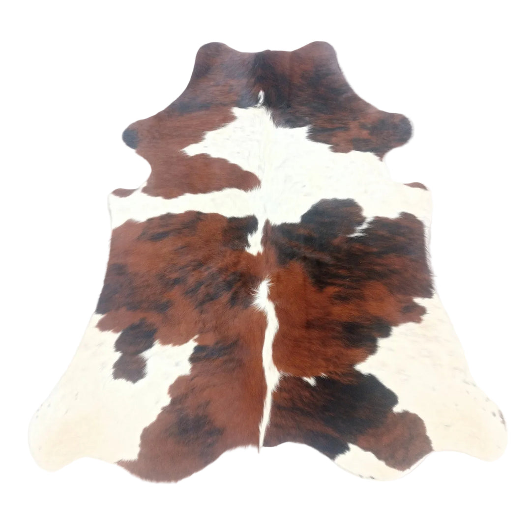 A cowhide rug with a natural brown and white spotted pattern, laid flat on a white surface.