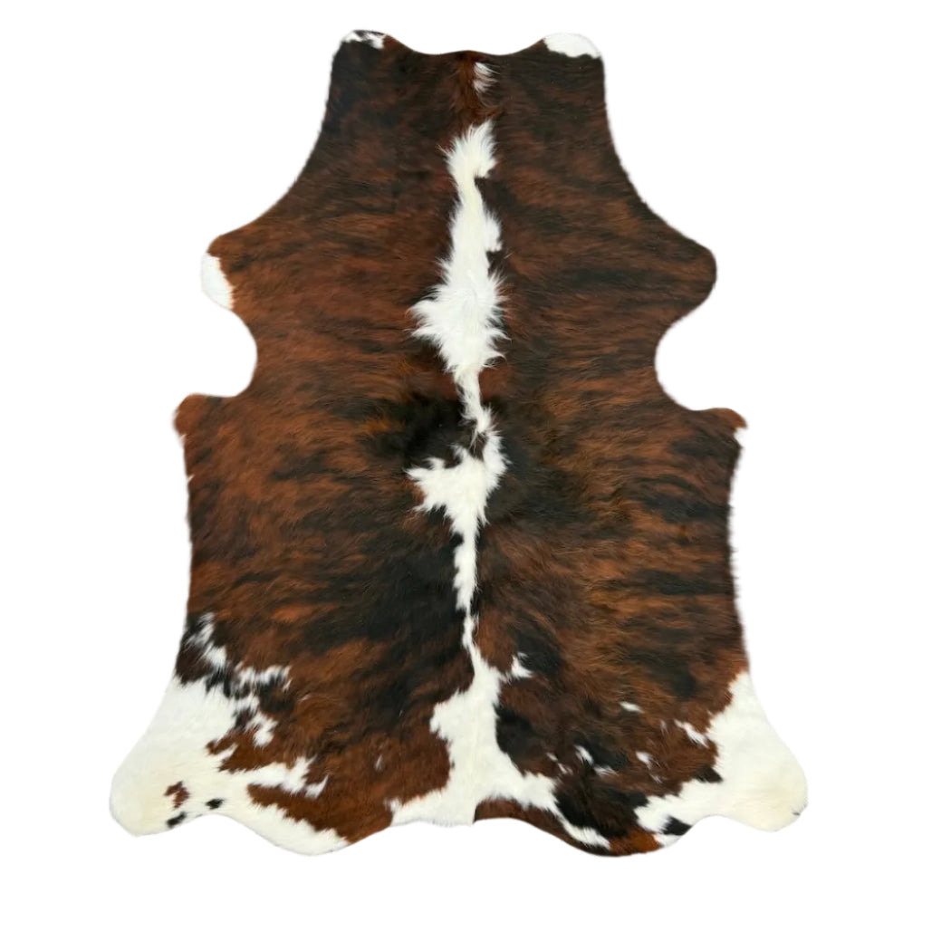 Brown and white cowhide rug laid flat on a gray wood plank floo