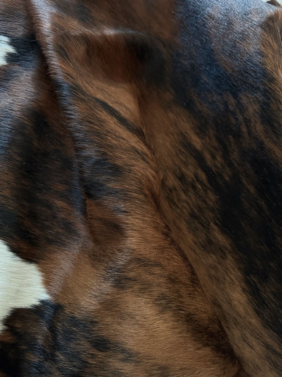 Close-up of a cowhide rug with brown, black, and white colours.