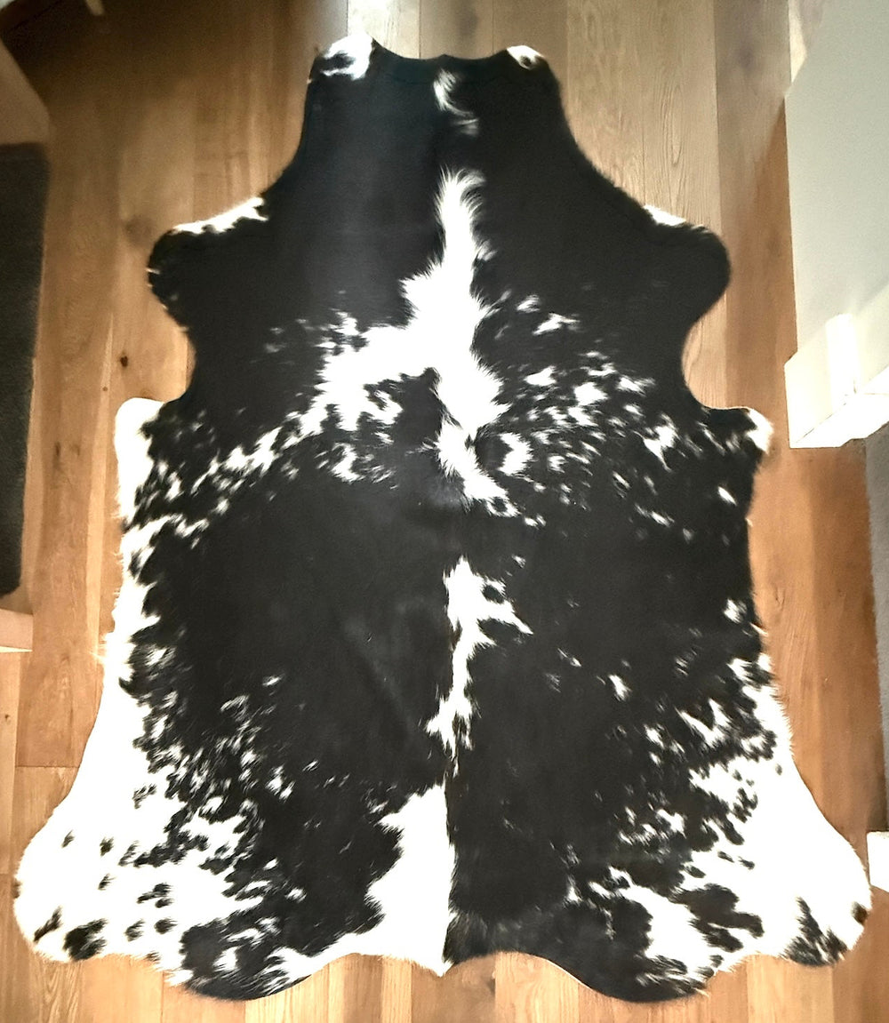 Black and white cowhide rug on a wooden floor