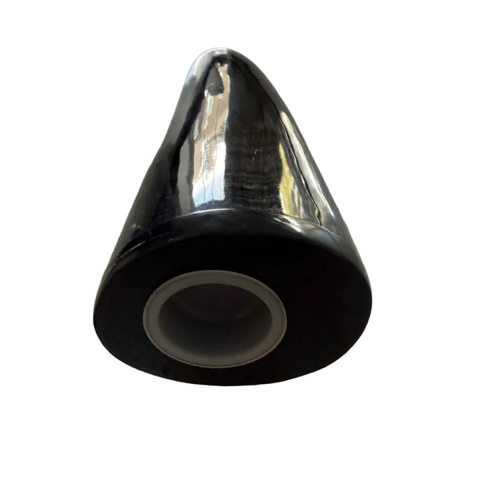 A glossy black cone-shaped cow horn with a circular opening, resting on a speckled light gray countertop.