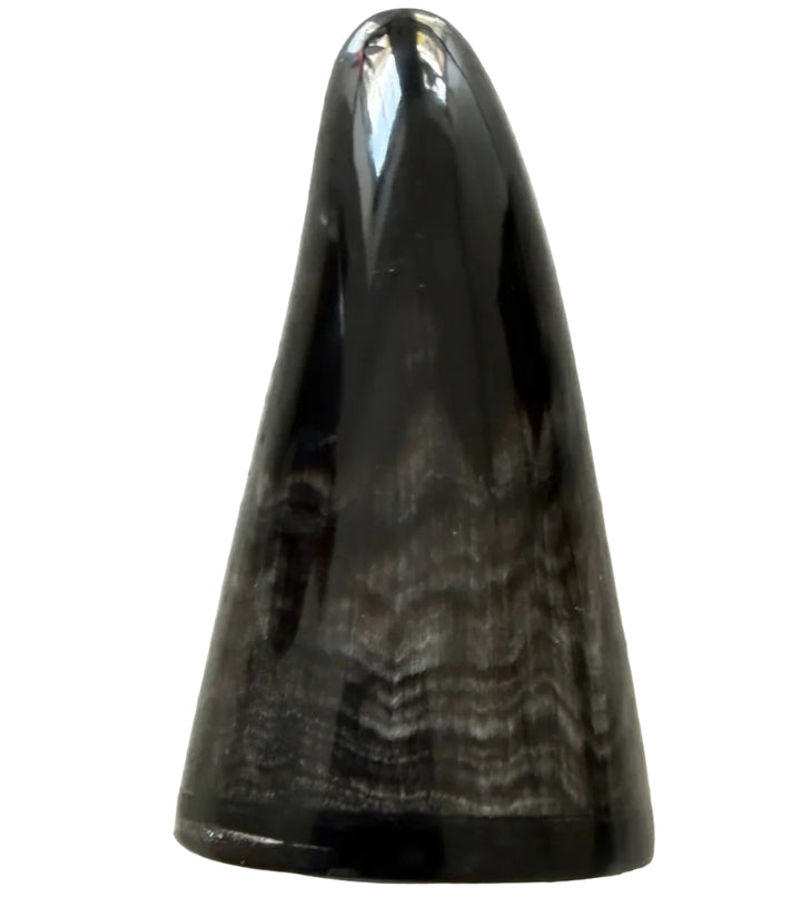 A polished black horn or bone cone-shaped object with natural marbled striations, resting on a speckled gray stone surface.