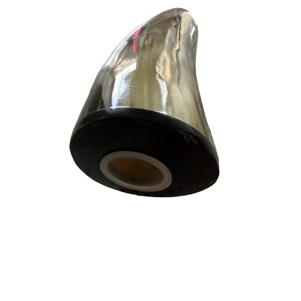 A polished metallic cow  horn or horn-shaped decorative object with a black circular base, lying on a speckled light gray countertop.