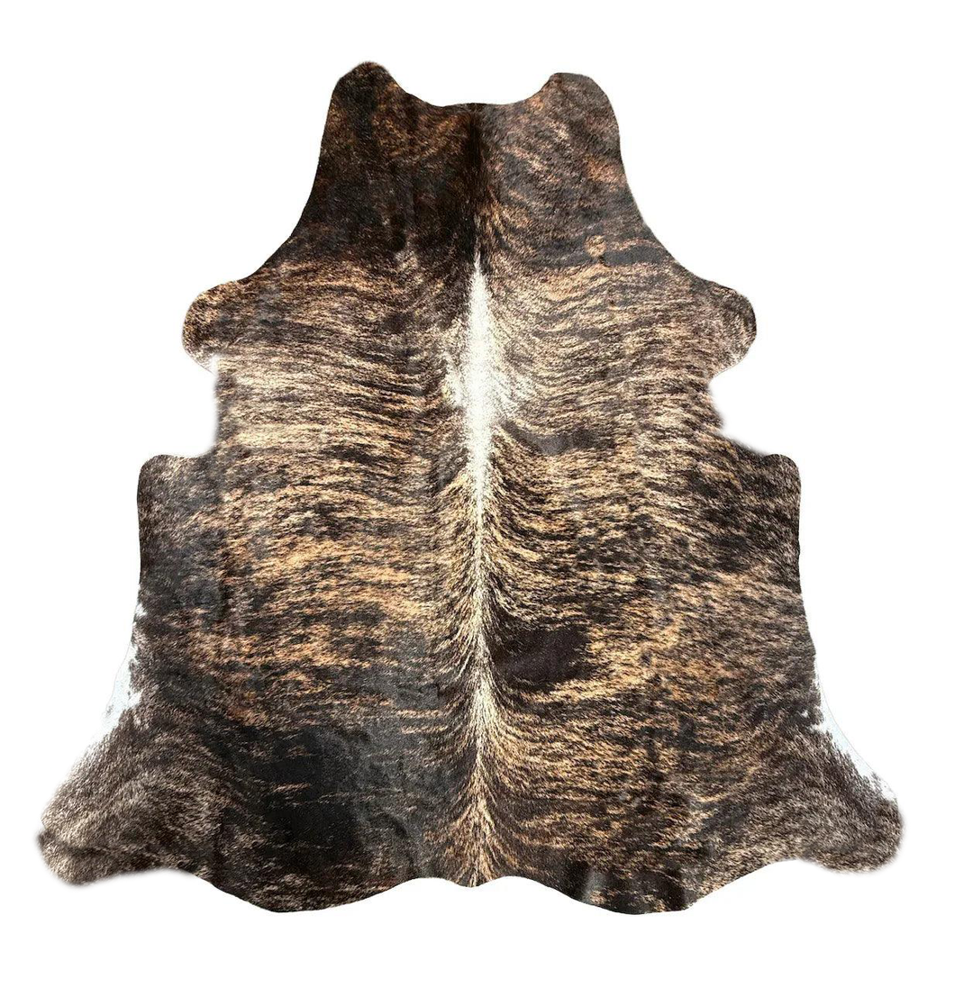 A natural cowhide rug with a dark brown and black mottled pattern and a lighter cream center, 