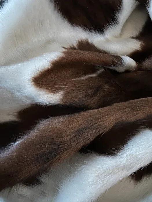 Premium Cowhide Rug AM287 from Cowhide Rugs London, showing a natural brown and white cowhide with a sleek, irregular shape.
