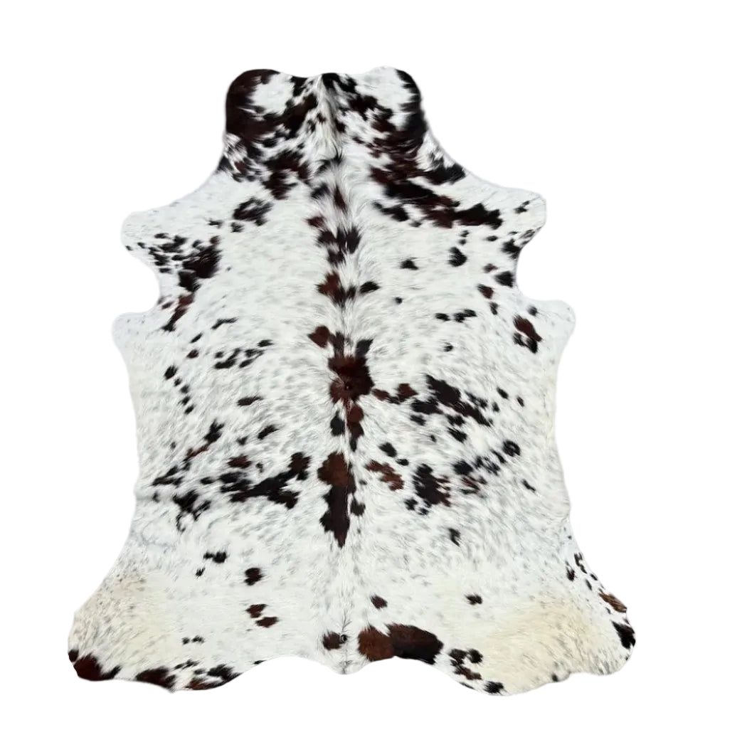 A natural cowhide rug with a black and white spotted pattern