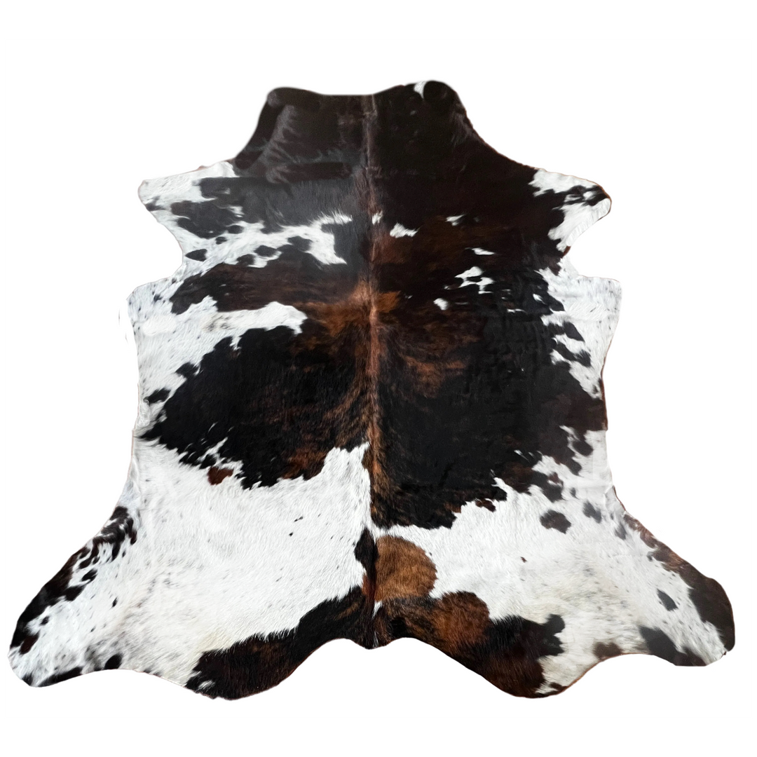 A natural cowhide rug with a black and white mottled pattern and some brown areas