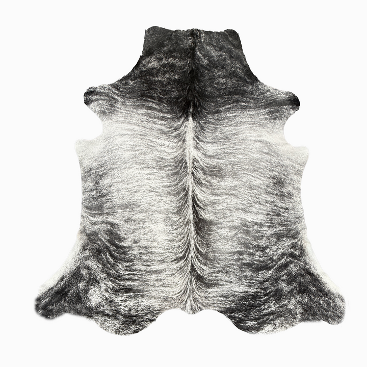 A natural grey cowhide rug with a distinct black and white gradient, transitioning from dark charcoal at the top to light cream at the bottom