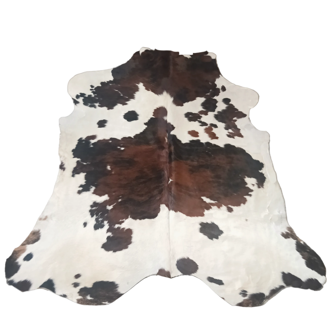 A natural cowhide rug with a brown and black spotted pattern on an off-white base