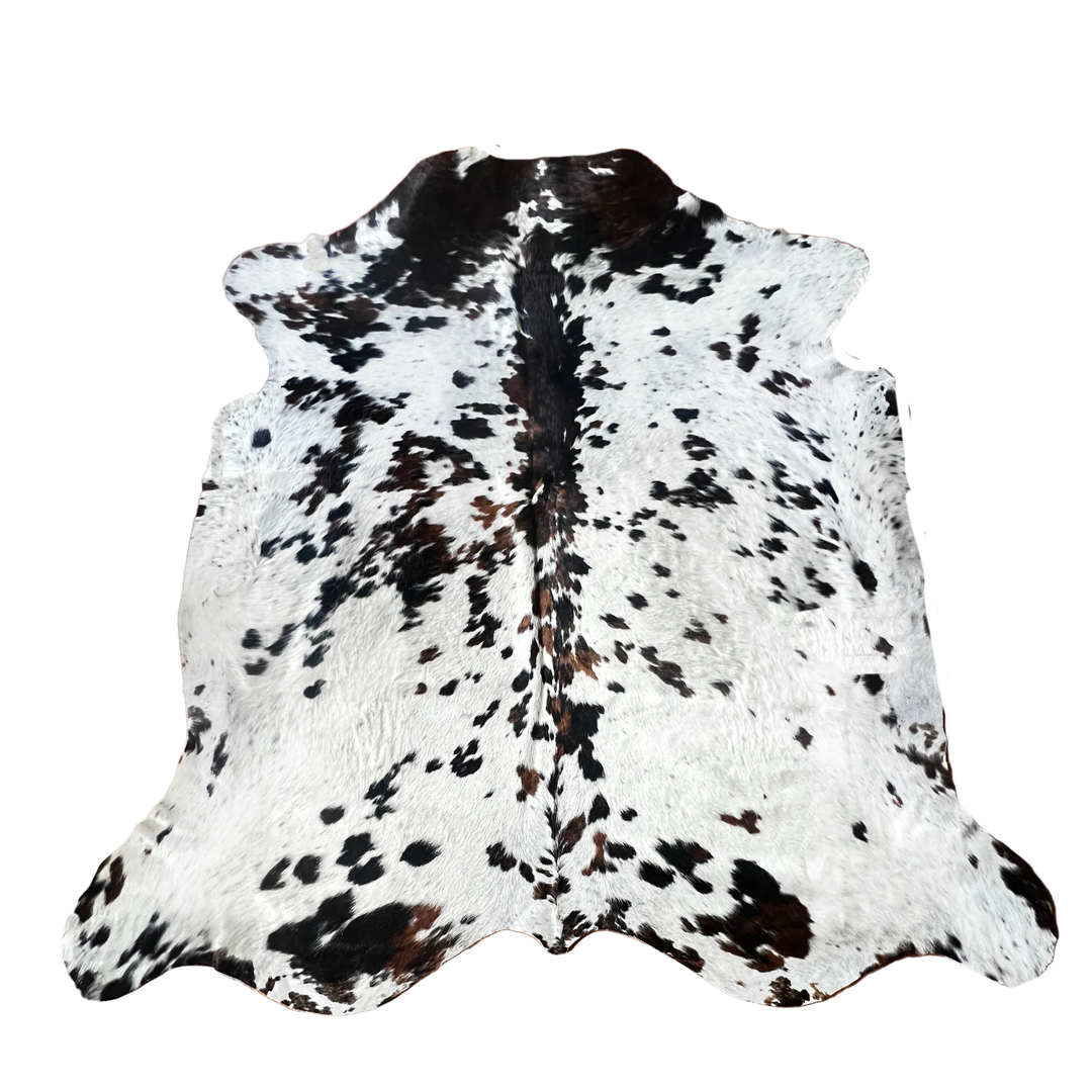 A natural cowhide rug with a black and white spotted pattern