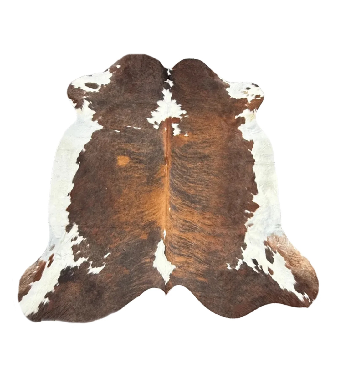 A natural cowhide rug with a classic brown and white spotted pattern, photographed flat against a solid white background.