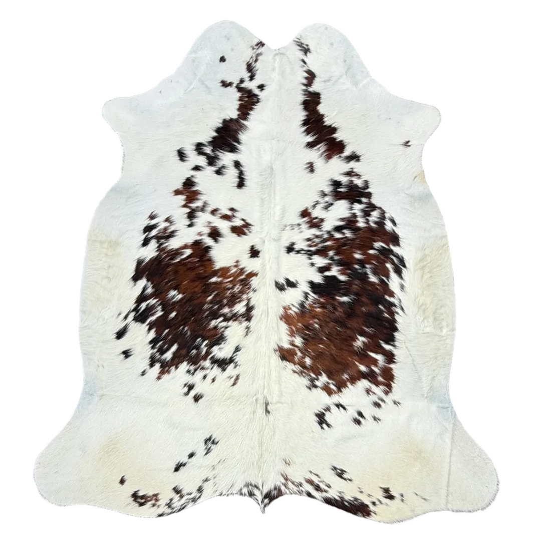 A natural cowhide rug with a brown and black spotted pattern 