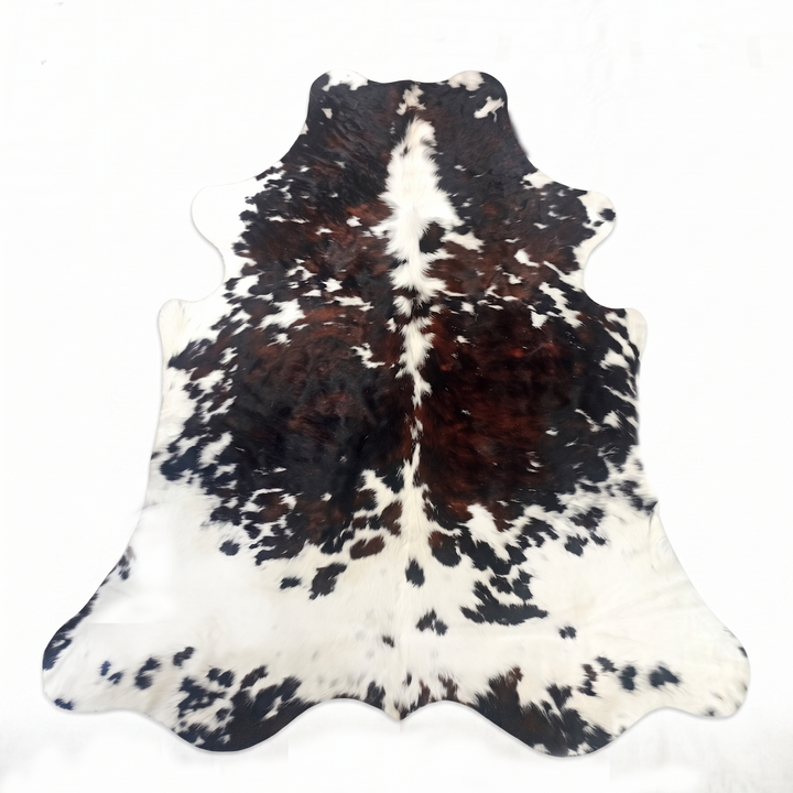 A natural cowhide rug with a black and white mottled pattern and a prominent dark brown center stripe, laid flat against a white background.