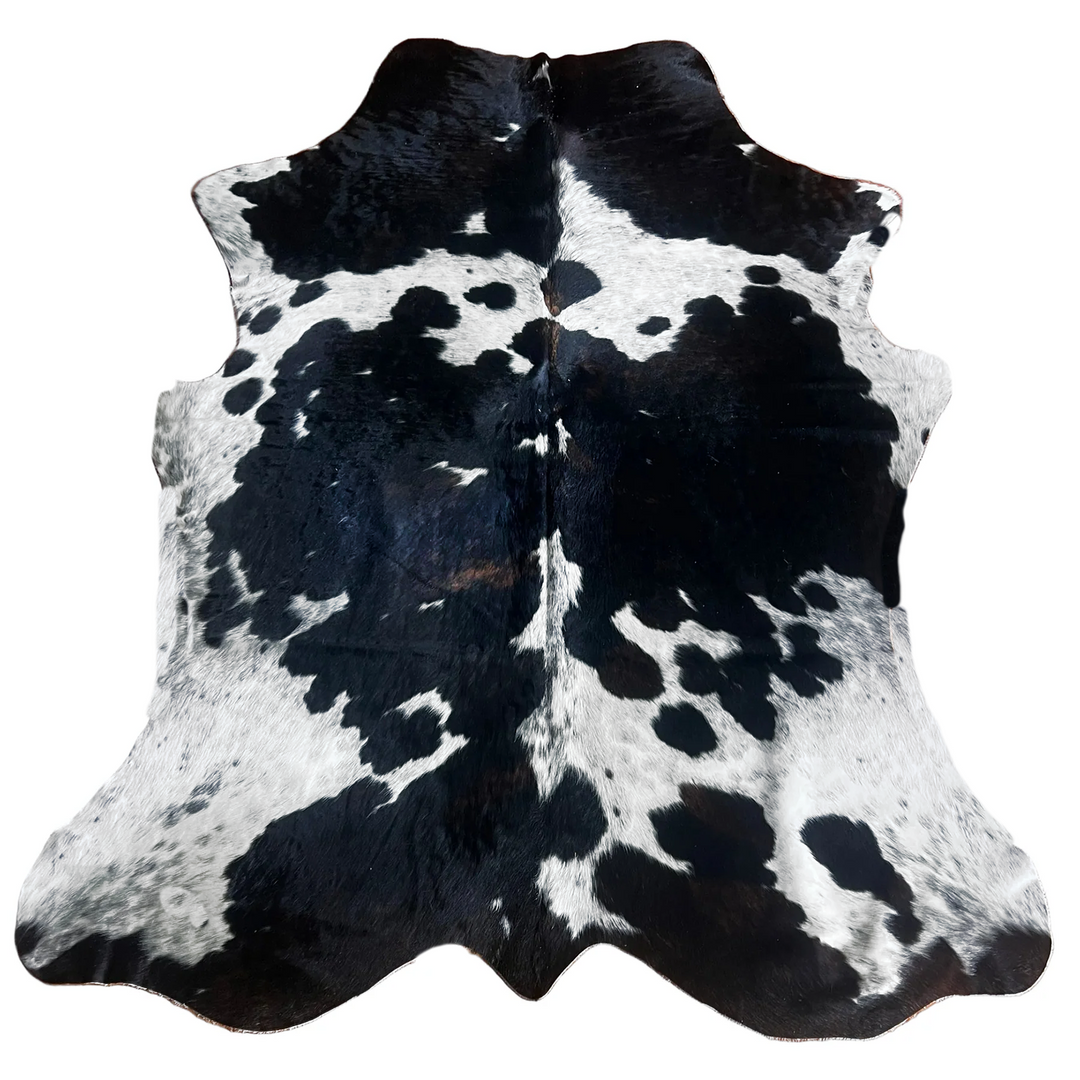 A black and white cowhide rug with a natural spotted pattern.
