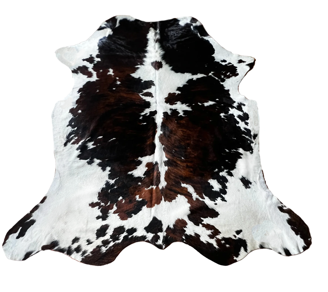 A natural cowhide rug with a classic black and brown spotted pattern on a white base
