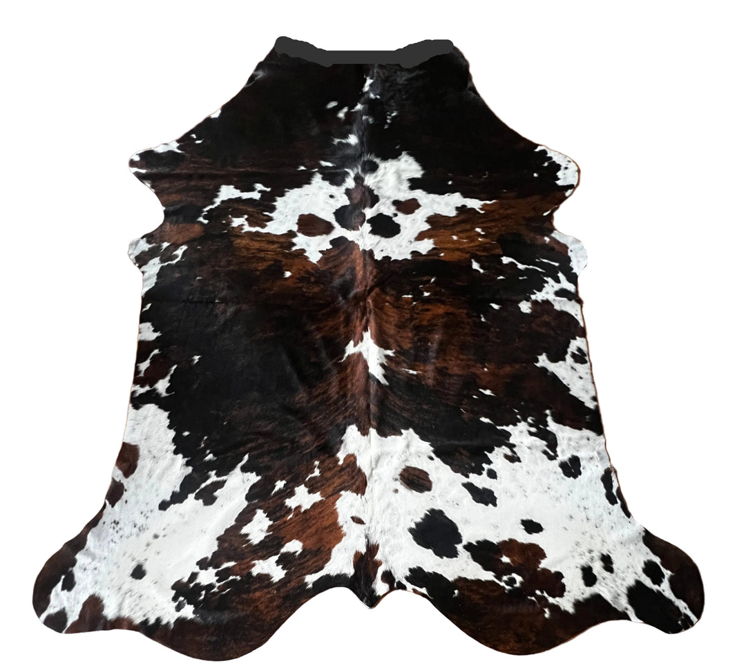 A natural cowhide rug with a classic black, brown, and white spotted pattern, laid flat against a solid white background.