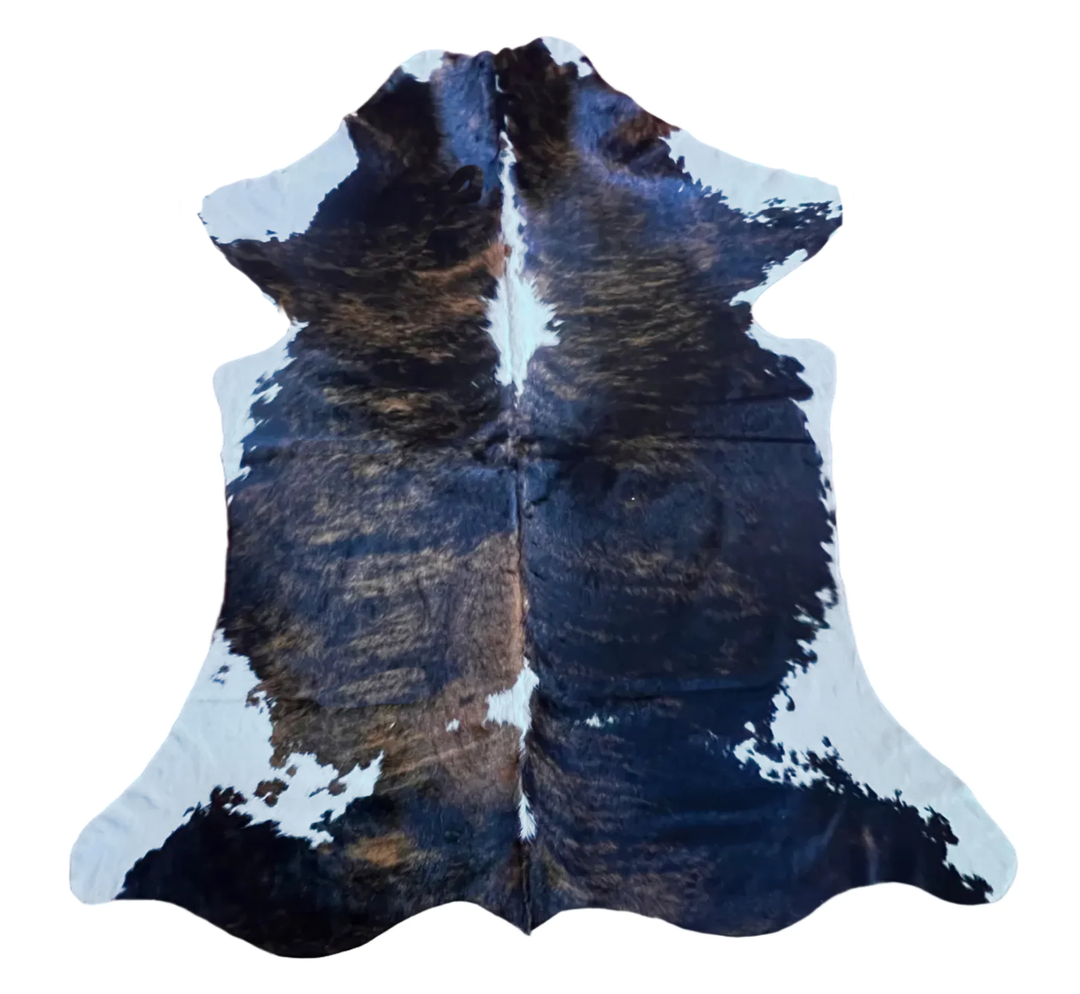 A natural cowhide rug with a black and white pattern and subtle brown undertones,