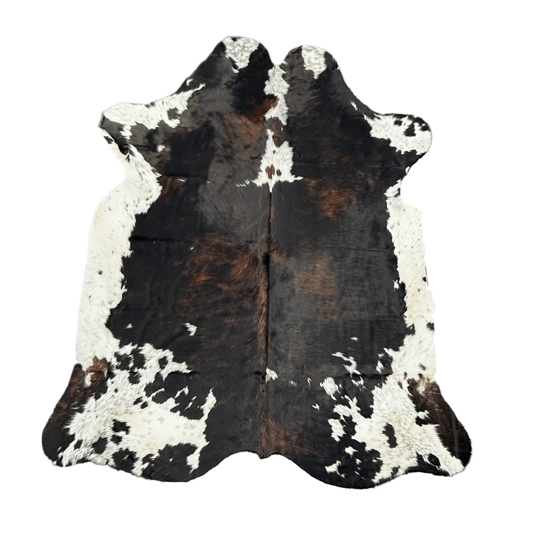 A natural cowhide rug with a black, brown, and white mottled pattern, 