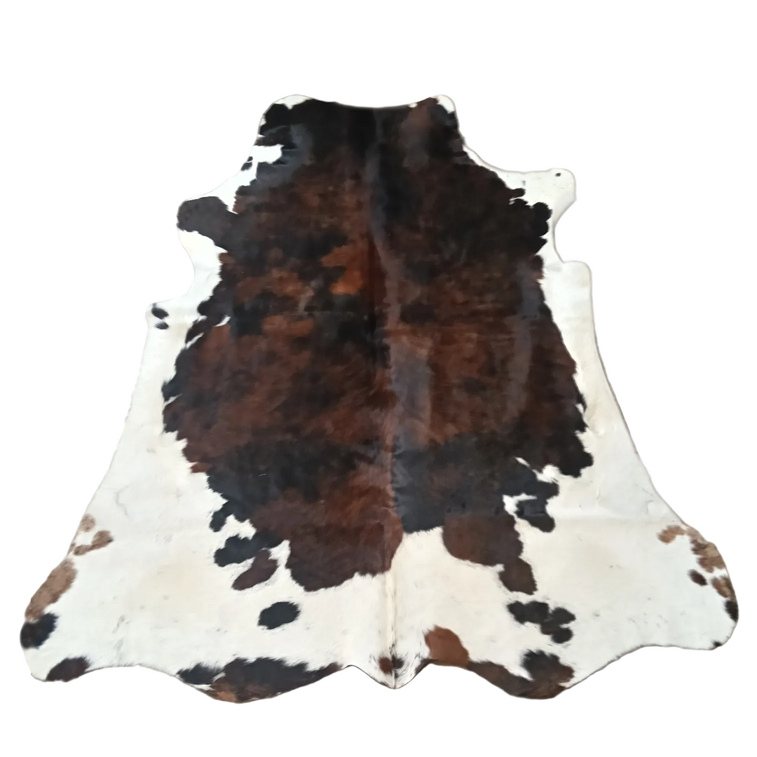A natural cowhide rug with a brown and black spotted pattern on an off-white base,