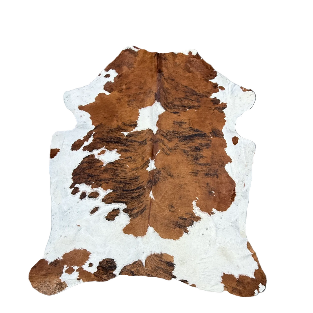 A natural cowhide rug with a brown and white spotted pattern, l